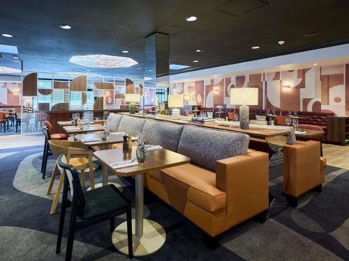 a restaurant with tables and chairs and a bar at Mercure Caen Cote De Nacre in Caen
