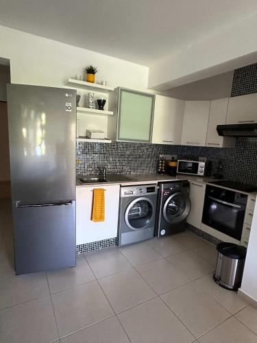 a kitchen with a refrigerator and a washer and dryer at WHTheGardens in Pyla