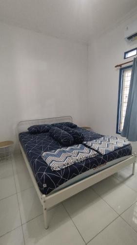 a bed with a blue comforter in a room at Rumah Senden Guesthouse in Yogyakarta
