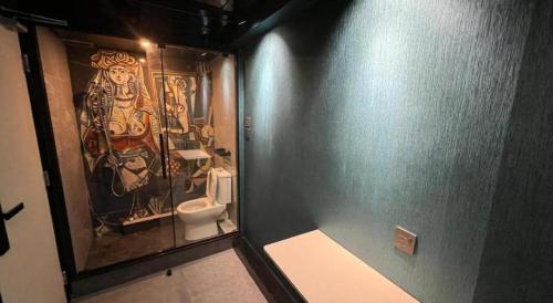 a bathroom with a toilet and a painting on the wall at Where Inn in Hong Kong
