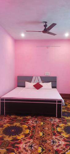 a bedroom with a bed with a pink wall at Hotel Sunrise inn in Nārdiganj