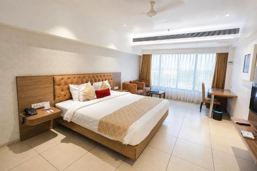 a hotel room with a large bed and a desk at Hotel Dwarkamai, A Pure Vegetarian Hotel in Nagpur