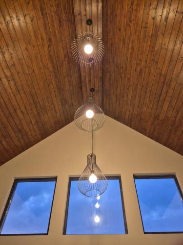 two lights hanging from a ceiling with three windows at Hill House Marisel in Mărişel