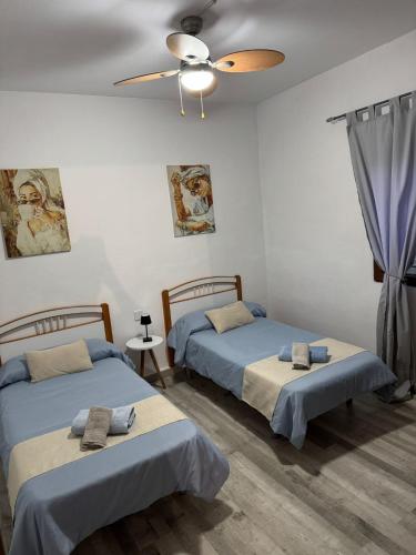 two beds in a room with a ceiling fan at Cortijo Batán in Dúdar