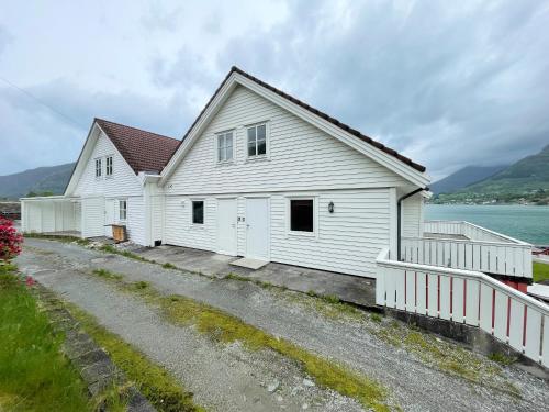 a white house with a fence next to a road at Fjord Apartments in Dimmelsvik