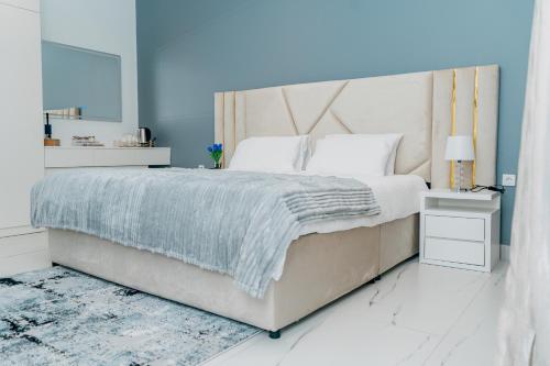a bedroom with a large bed with a blue wall at The Gardens in Marracuene