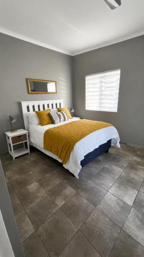 a bedroom with a large bed with yellow pillows at Stay a While Self catering - Close to Greenacres Hospital, free Wi-Fi, and secure parking in Newton Park