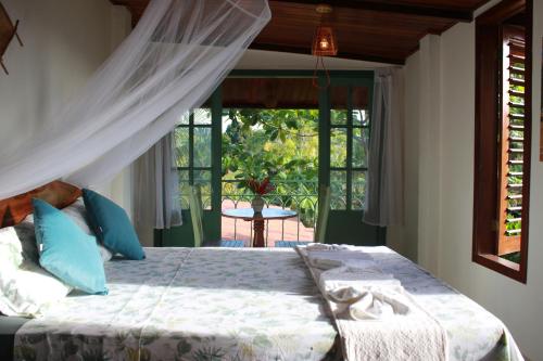 a bedroom with a bed with blue pillows and a window at Jardim UIXA in Ilha de Boipeba