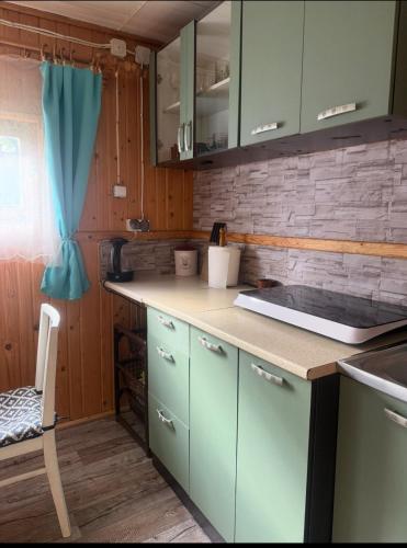 a kitchen with green cabinets and a counter top at Tleniowo Domek in Tleń