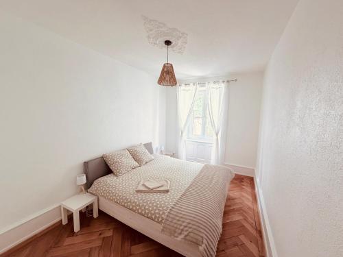 a small white bedroom with a bed and a window at Heure Cosy in La Chaux-de-Fonds
