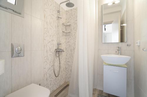 a white bathroom with a shower and a sink at Nirvana Homes in Vlachata