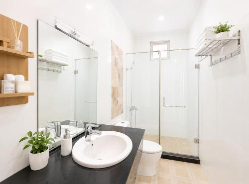 a white bathroom with a sink and a shower at Palette Anh Vu Hotel Phu Quoc in Phú Quốc