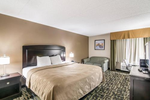 a hotel room with a bed and a chair at Quality Inn Rochester West in Rochester