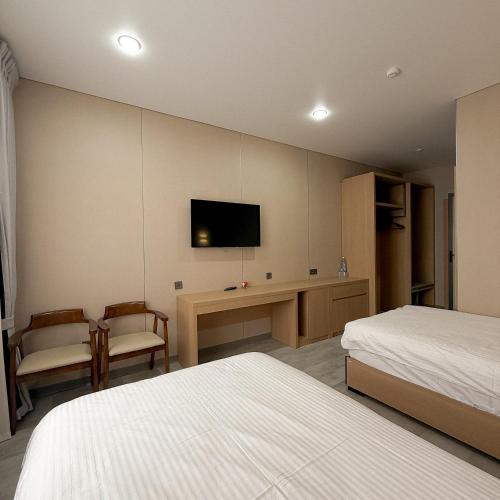 a hotel room with two beds and a tv on the wall at AiRom Hotel in Atyrau