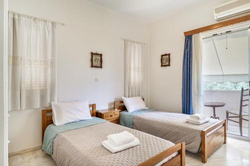 two beds in a room with a window at Kyma Arch House in Porto Heli