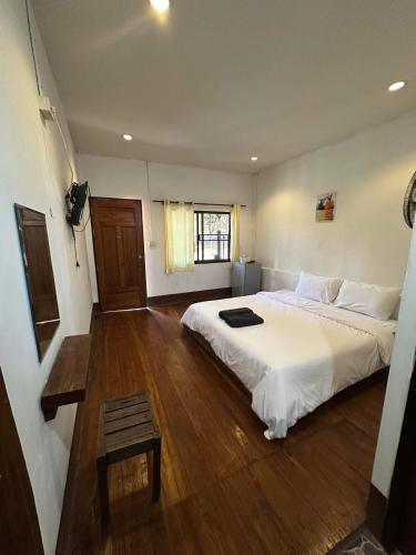 a bedroom with a large white bed and a wooden floor at Paihappy village in Ban Thung Pong