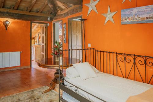 a bedroom with orange walls and a bed and a table at Casa La Romana in Ayllón
