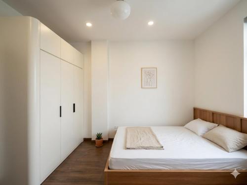a bedroom with a bed and a white wall at Urban Nest - Cầu Giấy in Hanoi