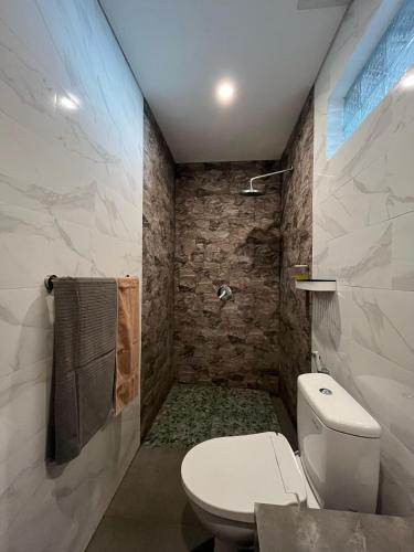 a bathroom with a toilet and a stone wall at Kalih Homestay Bali in Kuta