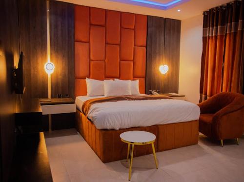 a bedroom with a large bed and a chair at Maxbliss Optimum Royal Hotel in Benin City
