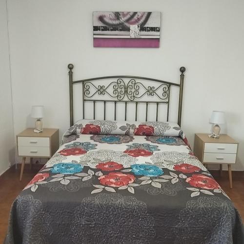 a bedroom with a bed with a floral bedspread at Casas los Rosales in Guadix