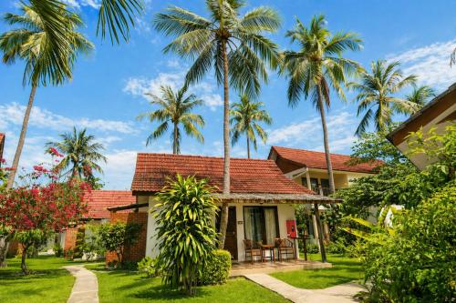 a house with palm trees in front of it at Frangipani Langkawi Resort in Pantai Cenang