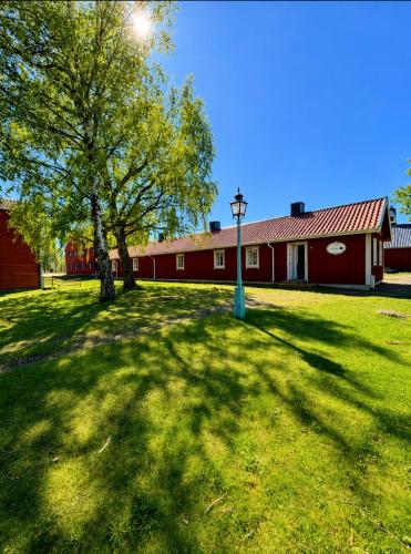 a red barn with a tree and a light in the grass at Valla Vandrarhem in Linköping