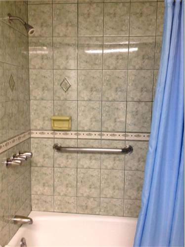 a shower with a blue shower curtain next to a tub at Walls Motel Long Beach in Long Beach