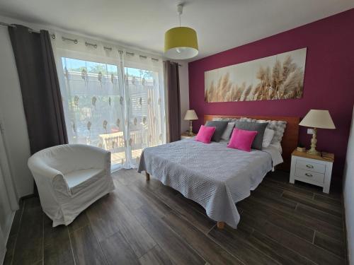 a bedroom with a bed with pink pillows and a chair at Superbe villa avec piscine in Bras