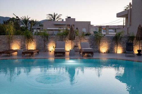 a swimming pool with two lounge chairs next to a building at Stella Maria Hotel & Suites in Malia