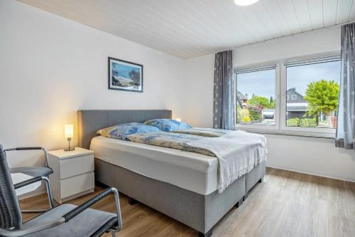 a bedroom with a bed and a chair and a window at Ferienhaus Plüschenworth in Drochtersen