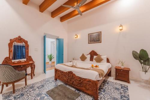 a bedroom with a bed and a desk and a chair at La casa Verde 4BHK with Private Pool, Baga in Baga