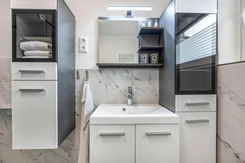 a white bathroom with a sink and a mirror at Ferienhaus Plüschenworth in Drochtersen