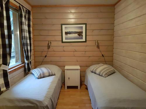 two beds in a room with wooden walls at Rivitahko 5 in Tahkovuori