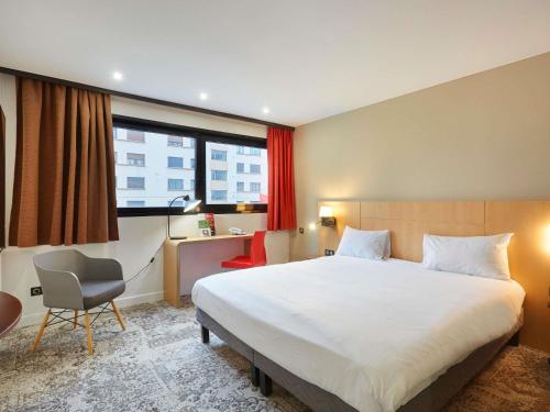 ein Hotelzimmer mit einem großen Bett und einem Stuhl in der Unterkunft ibis Annemasse-Genève in Ambilly
