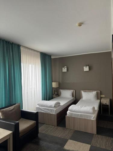 a hotel room with two beds and a couch at Aktau Hotel in Aktau