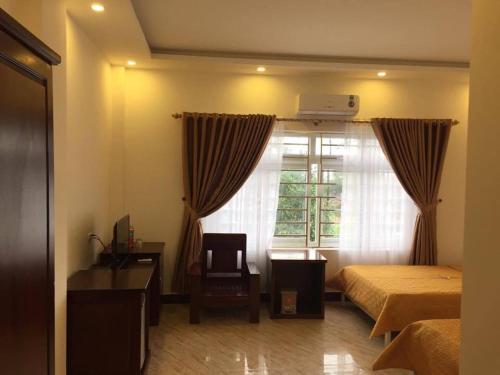 a bedroom with a bed and a window and a chair at Binh Minh Dien Chau Hotel in Diễn Châu