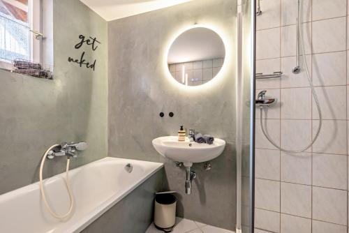 a bathroom with a sink and a bath tub and a mirror at Ferienwohnung Lea La Milan in Stockach