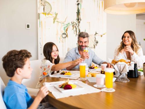 a group of people sitting around a table eating food at Hotel Jequitimar Guaruja Resort & Spa by Accor in Guarujá