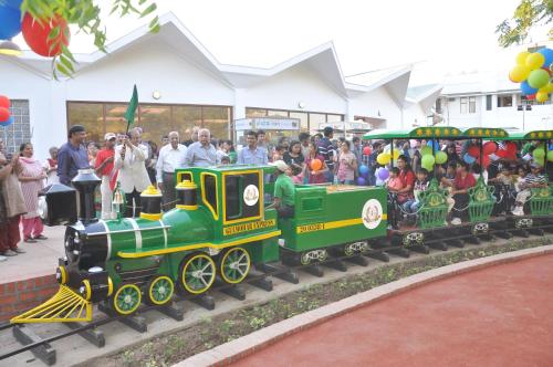 a small green train with a crowd of people at Gulmohar Greens Golf & Country Club in Sānand