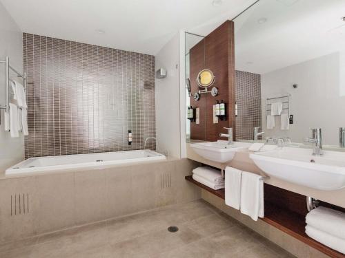 a bathroom with two sinks and a bath tub at Pullman Sydney Olympic Park in Sydney