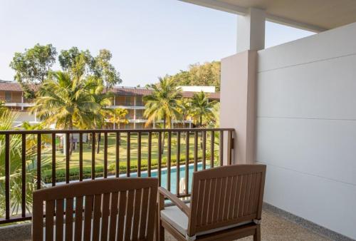 a balcony with two chairs and a view of a pool at Katathani Phuket Beach Resort - SHA Extra Plus in Kata Beach