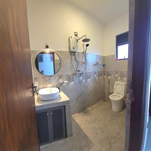 a bathroom with a sink and a mirror and a toilet at Urban tropics in Colombo