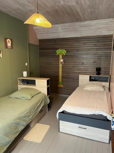 a bedroom with two beds and a palm tree on the wall at le tilleul in Caumont