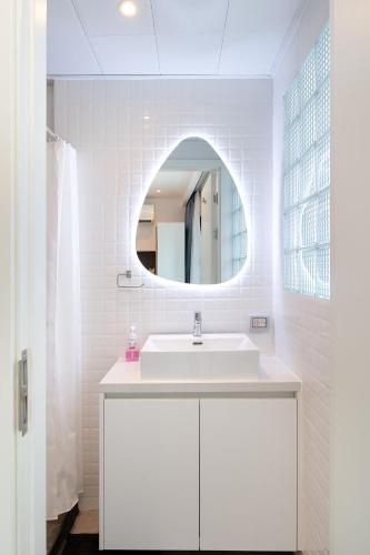 a white bathroom with a sink and a mirror at Mac's House in Bangkok