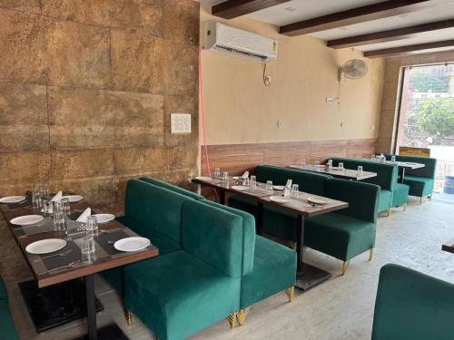 a restaurant with green chairs and tables in a room at Hotel Green Land in Mathura