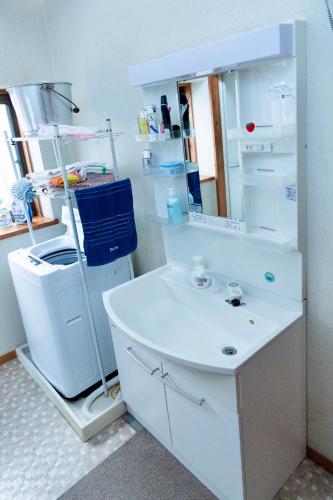 a white bathroom with a sink and a mirror at 古民家一棟貸 鴨部巣 kamobese in Kochi