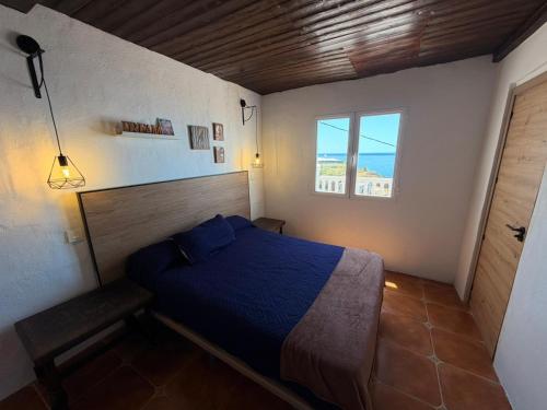 a bedroom with a blue bed and a window at Enamórate con vistas al mar en La Marina House in La Alcazaba