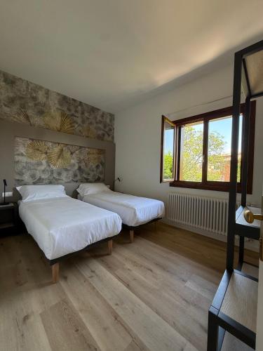 a bedroom with two beds and a window at LEON D'ORO - Art Hotel in Pieve di Soligo