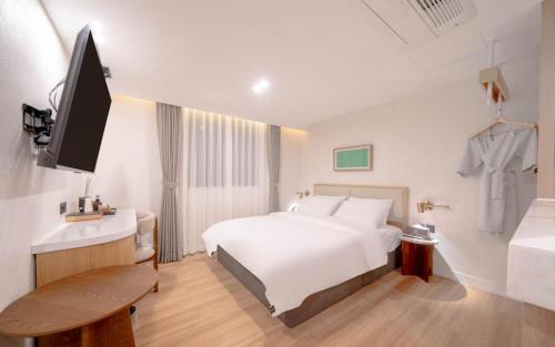a hotel room with a white bed and a television at H-Avenue Hotel Haeundae in Busan